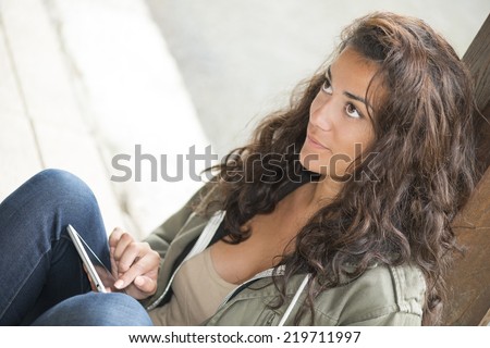 Put on her knees a woman using digital tablet with touch screen finger. She looking away to the left copy space. Closeup