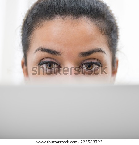 Facial expression of concentration. Woman\'s eyes working behind her display computer. Sparse and copy space