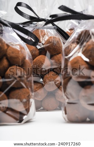 Gifts of Christmas chocolate truffles in luxury plastic bags with black ribbon. Closeup. Shooting on white background in studio.