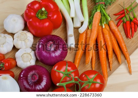 Red onion, carrots, white onion, tomatos, carrot and garlic on a wooden board