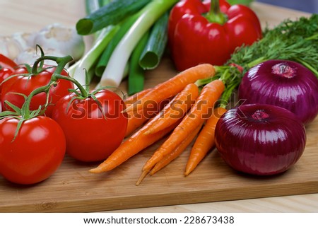 Red onion, carrots, green onion, scallion, tomatos and red pepper on a wooden board