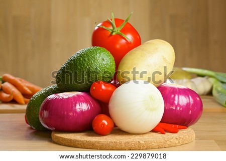 Red and white onion, avocado, tomatos, red pepper and chilli pepper on a wooden board