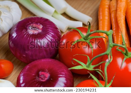 Red onion, carrots, green onion, scallion, tomatos and red pepper on a wooden board