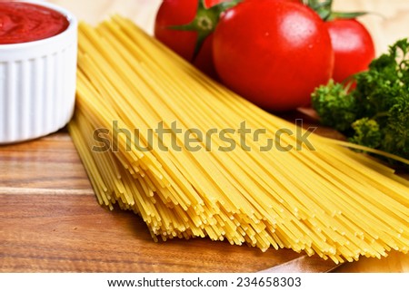 Bunch of italian spaghetti with tomato sauce and tomatoes on wooden brown background