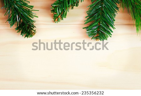 Green fir-tree branches on wooden background. Space for text
