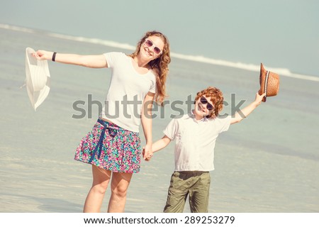 Mother and red haired son having family time on holidays walking along the beach. Travel, holiday, vacation concept
