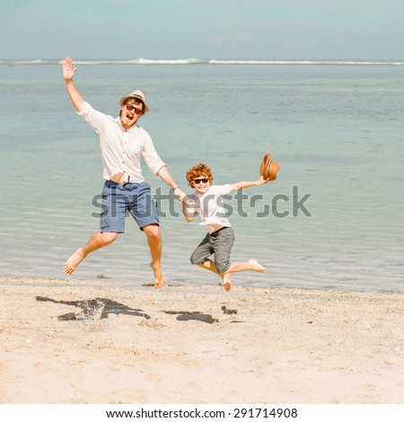 Hipster father with beard and red haired son playing on the beach at the summer day. Vacation, happy and friendly family, holidays concept