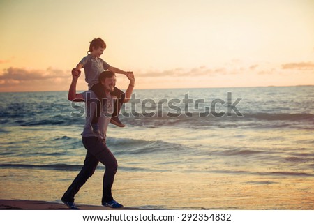 Happy father and son having quality family time on the beach on sunset on summer holidays. Lifestyle, vacation, happiness, joy concept