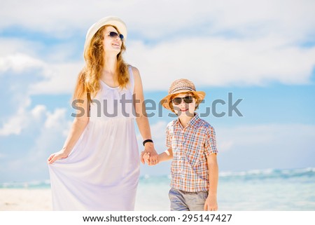 Happy mother and son walk along the white sand ocean beach having great family time on vacation on Pandawa Beach, Bali. Paradise, travel, vacation concept