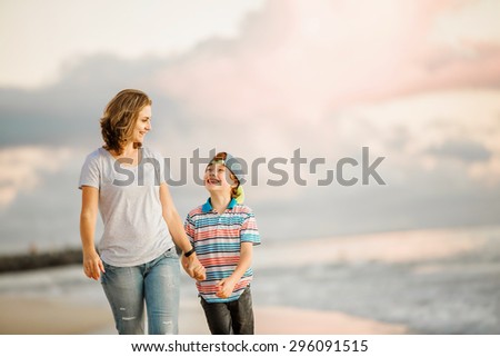 Young happy beautiful mother and her son having fun on the beach on sunset. Positive human emotions, feelings concept