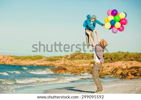 Happy father and son having quality family time on the beach playing with balloons on summer holidays. Lifestyle, vacation, happiness concept