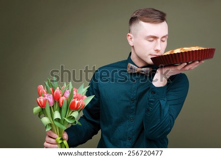 A man in a shirt and tie with a bouquet of pink tulips and pie