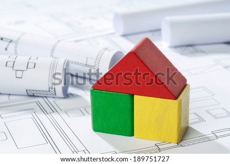 House of differently colored building blocks on blueprint.
