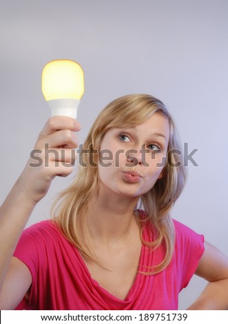 Young woman holding a energy saving lamp in hand.