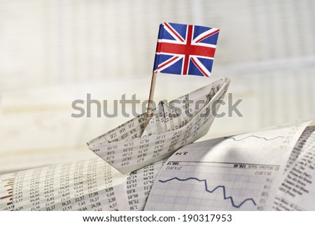 Paper ship with British flag on stock market news.
