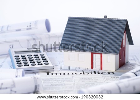 Model house, blueprints, calculator and real Estate adverts with the german word 