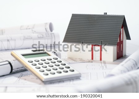Construction costs symbolized by an architectural model, blueprints and calculator.