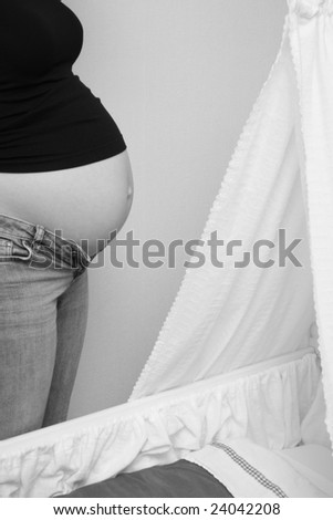 Pregnant woman standing next to a cradle