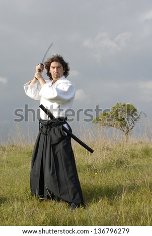 young aikido man with a sword, outdoor