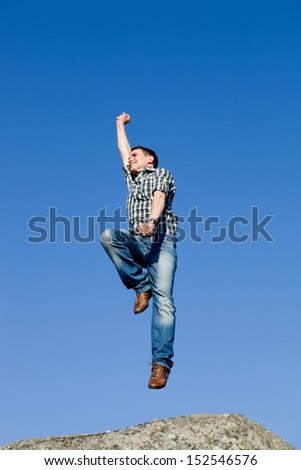 young happy man, with a big jump, on top of a rock