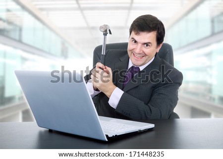 happy businessman with a hammer smashing a laptop, at the office