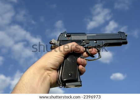 Pistol in hand and the sky as background