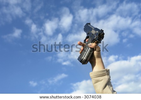 gun in a child hand with clouds in the sky