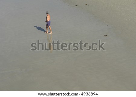 old man alone on the wet sand at the beach