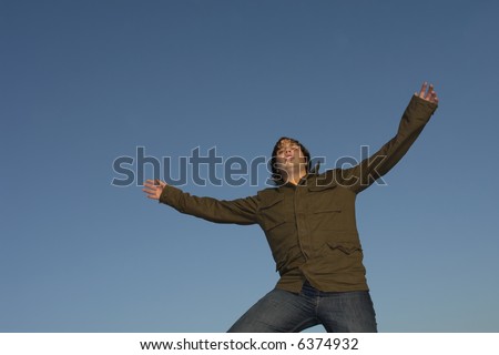 young man with arms wide open and the sky