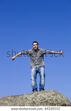 young happy man, starting a big jump, on top of a rock
