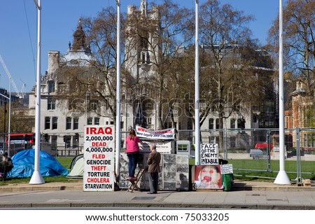 LONDON - APRIL 8: Peace campaigners hang signs in Parliament Square, in front of the Houses of Parliament, to protest against the UK involvement in the Iraq war on April 8, 2011 in London, England.