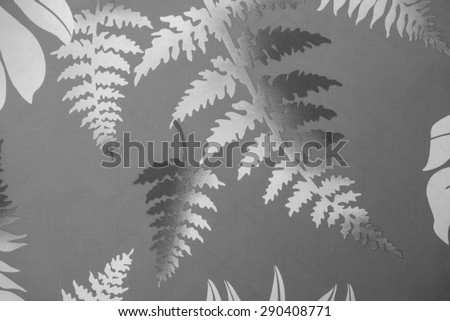 Vintage Polynesian cloth fragment of white and gray ferns and leaves against a dark gray background.
