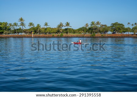 Honolulu, Hawaii, USA, June 28, 2015: Dawn view of Waikiki\'s Ala Wai Harbor as a solo outrigger canoe paddler departs the harbor on a voyage to Molokai.  Outrigger canoes are popular in Hawaii.