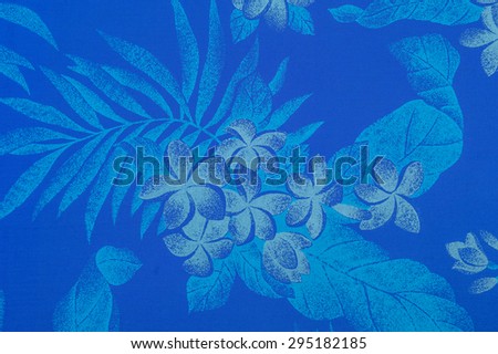 Polynesian/Hawaiian cloth fragment with white Plumeria blossoms and turquoise leaves against a faded royal blue background.