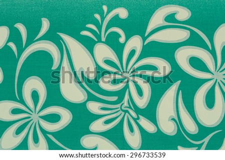 Vintage tropical  cloth fragment in a white floral  jungle design against a faded blue background.