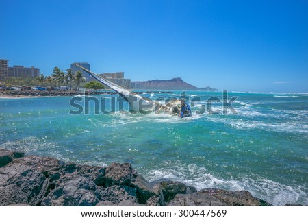 Honolulu, Hawaii, USA, July 27, 2015:  Morning view of Waikiki and Diamond Head as a navigation error finds a sailboat on the beach in large surf and strong winds.  Wave haze obscures the horizon.