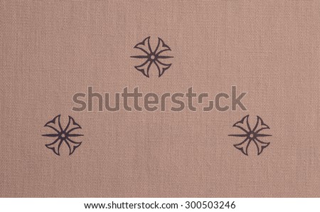 Vintage cloth fragment with tan pattern against a textured and graduated rose background.