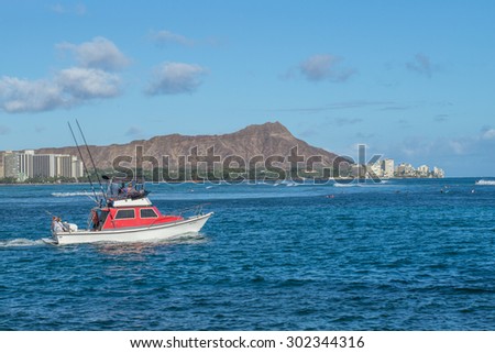 Honolulu, Hawaii, USA, August 2, 2015:  Evening departure by a small sport fishing boat from the Ala Wai Harbor with Waikiki and Diamond Head in the background.  Sport fishing is increasingly popular.