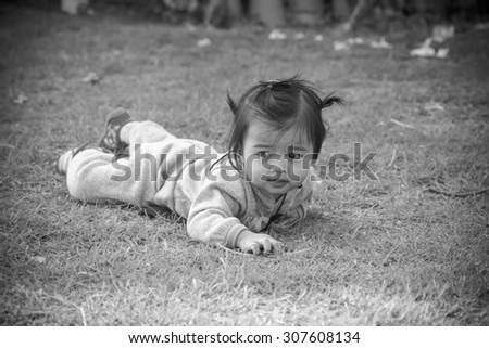Toddler child, girl or girl, learning to walk, trying to get up from grass lawn.