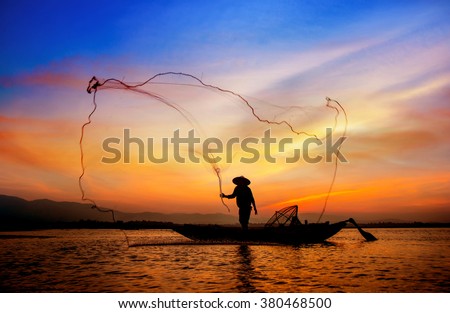 Silhouette of traditional fishermen throwing net fishing lake at sunrise time.(The casting people living along the River)