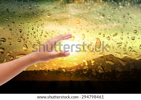 women hand touch the bokeh and water drops on  mirror sunset  background