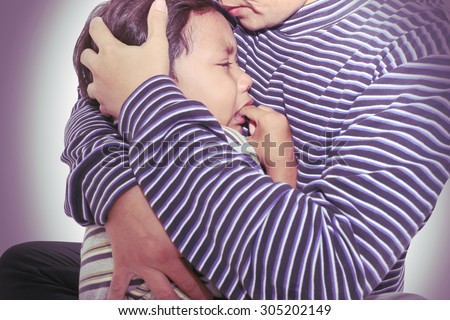 Little boy crying in his mother's arms.