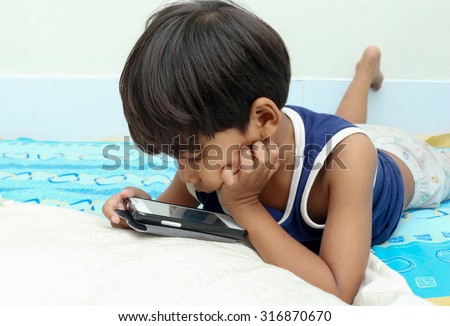 Little boy play a smart phone on the bed