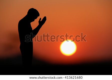 A silhouette of islamic praying at sunset.