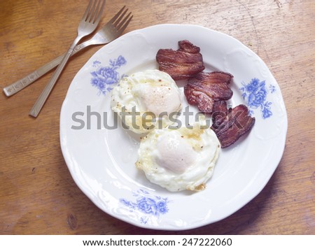 Breakfast plate with eggs and bacon on wooden table
