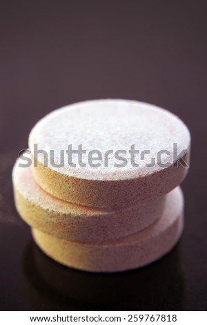 A stack of three effervescent tablets on purple background.