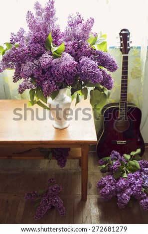 Romantic interior design with lilac flowers and red guitar