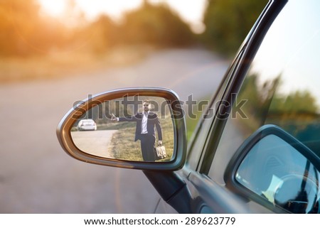 Hitchhiking man in the rearview mirror