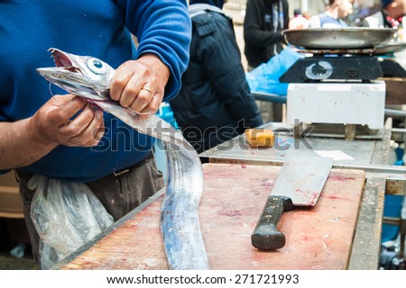 Hands of a fish seller holding a paddle fish for sale in the fish market of Catania, Sicily