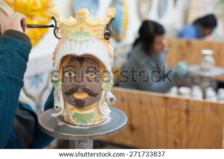Ceramic head of an arab soldier being finished by a decorating artisan of Caltagirone in a local workshop of the town